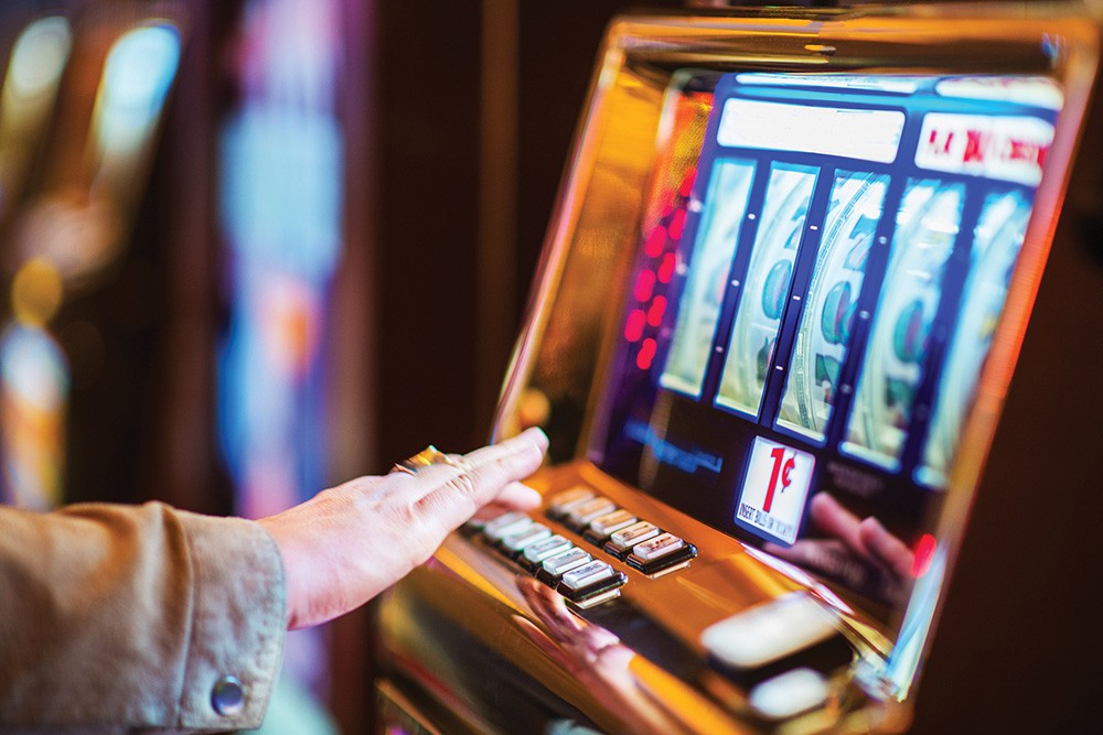 Someone playing a slot machine. A hand wearing a ring reaches out to press another button