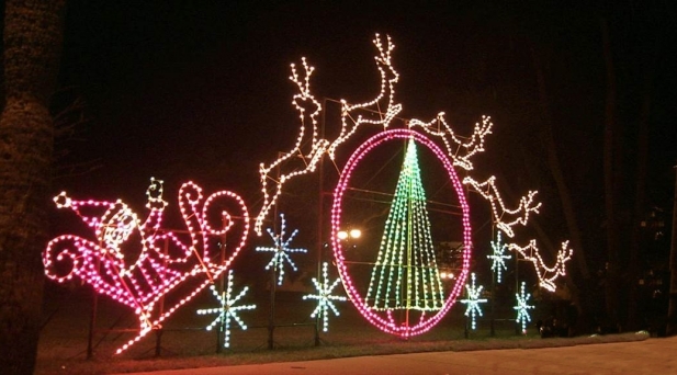 Lighted ground display of santa and reindeers flying over christmas tree